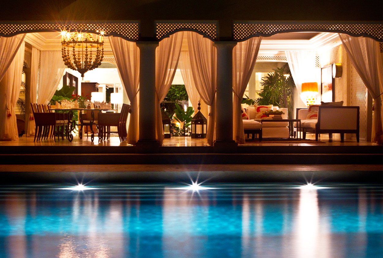 Outdoor pool, dining, and seating area at night in Roaring Pavilion, Jamaica